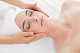 Hands massaging woman's face at beauty spa