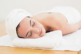 Beautiful woman with eyes closed on towel at beauty spa