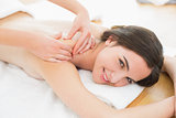 Smiling beautiful woman enjoying shoulder massage at beauty spa