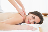 Smiling woman enjoying shoulder massage at beauty spa