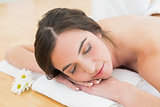 Woman resting with eyes closed on towel at beauty spa