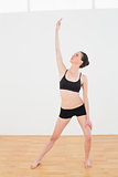 Sporty woman stretching hand in fitness studio