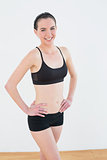 Smiling toned woman with hands on hips in fitness studio