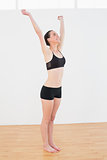 Cheerful sporty woman stretching hands in fitness studio