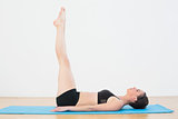 Sporty woman stretching legs upwards in fitness studio