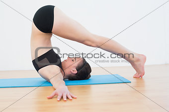 Fit woman doing the plough posture in fitness studio