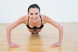 Young woman doing push ups in fitness studio