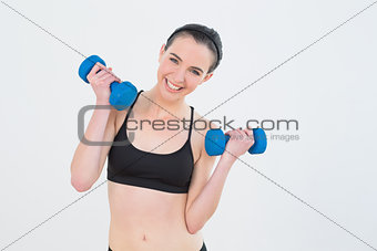 Woman with dumbbells against wall at fitness studio