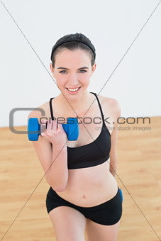 Smiling woman with dumbbell at fitness studio