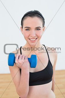 Smiling young woman with dumbbell at fitness studio