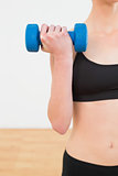 Mid section of a young woman exercising with dumbbell