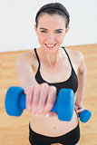 Smiling woman with dumbbells at fitness studio