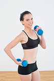 Smiling woman with dumbbells at fitness studio