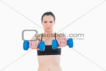 Portrait of a serious young woman with dumbbells
