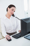 Businesswoman using computer and telephone in office