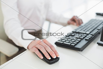Mid section of businesswoman using mouse in office