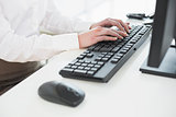 Mid section of businesswoman using computer keyboard in office