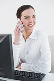 Businesswoman using mobile phone in front of computer