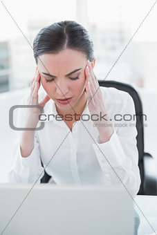 Businesswoman suffering from headache in front of laptop
