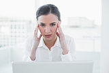 Businesswoman suffering from headache in front of laptop