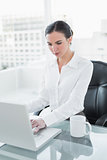 Concentrated businesswoman using laptop in office