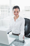 Businesswoman with coffee cup while using laptop at desk