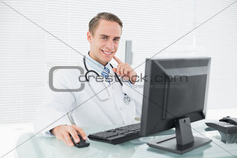 Smiling male doctor with computer at medical office