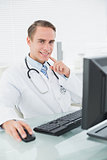 Smiling male doctor with computer at medical office