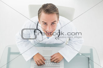 Overhead portrait of a smiling doctor using laptop
