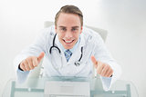 Overhead portrait of smiling doctor with laptop gesturing thumbs up