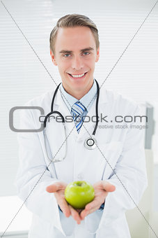 Portrait of a smiling male doctor with a green apple
