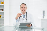 Smiling male doctor with digital tablet at medical office