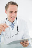 Smiling male doctor looking at digital tablet