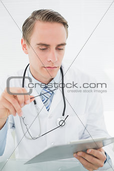 Serious male doctor looking at digital tablet
