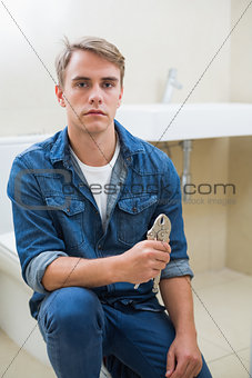 Serious male plumber with wrench against sink