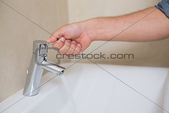 Plumber's hand opening a water tap at bathroom
