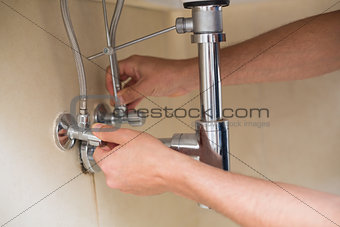 Extreme Close up of a plumber's hands and washbasin drain