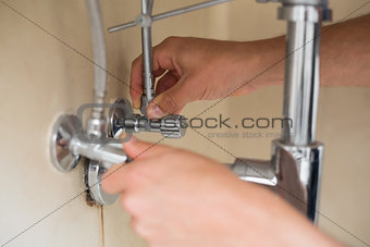 Close up of a plumber's hands and washbasin drain