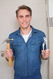 Smiling handyman holding wrench and hammer