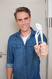 Smiling young handyman holding out wrench