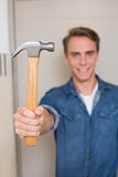 Smiling young handyman holding out hammer