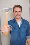 Smiling young handyman holding out hammer