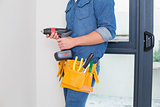 Mid section of a handyman with drill and toolbelt