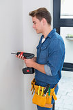 Handyman using a drill with toolbelt around waist