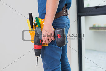 Side view mid section of a handyman with drill and toolbelt