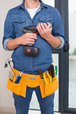 Mid section of a handyman with drill and toolbelt