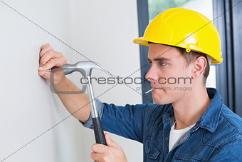 Handyman hammering nail in wall