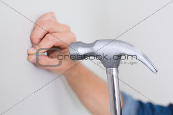 Hands hammering nail in wall