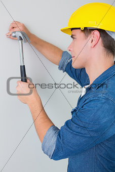 Side view of handyman hammering nail in wall
