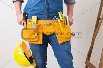Mid section of handyman with toolbelt and hard hat